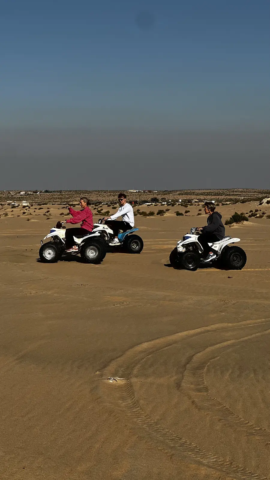 Riders on quad bikes crossing the desert dunes near Dammam