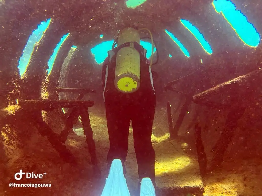 Diver swimming through a sunken structure window at the underwater museum